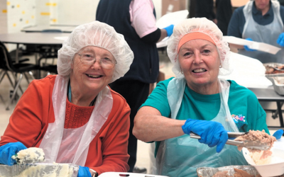 Two happy volunteers serving food at the BMH 4th Annual Community Drive-Thru Thanksgiving Dinner