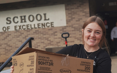 Young female volunteer carrying a supply box at the BMH 4th Annual Community Drive-Thru Thanksgiving Dinner