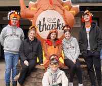 Student volunteers posing beside an inflatable turkey at Boone Memorial Health Community Thanksgiving Dinner